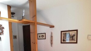 A wooden sofa with cushions in a room with a herringbone floor, a wooden beam structure, and two framed pictures on the wall. - MORGEX 923 _Monte Bianco_Valdigne (Morgex)
