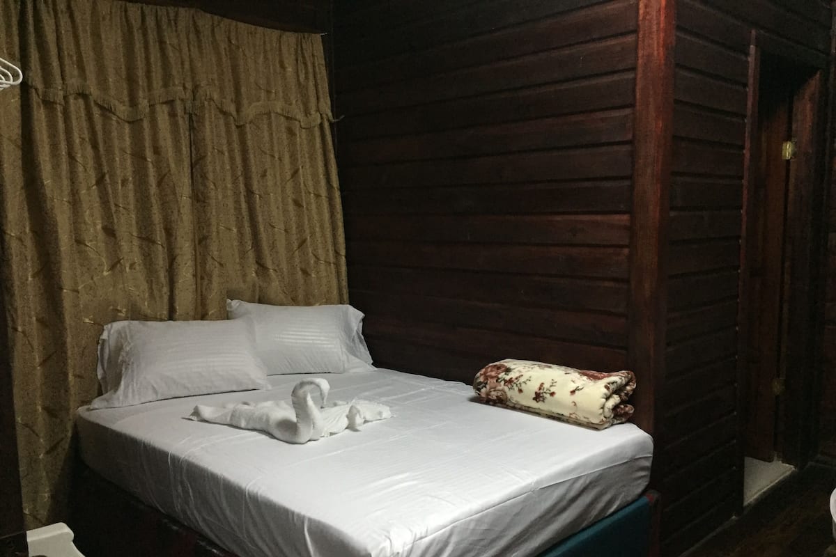 A bed with white linens and a swan-shaped pillow.