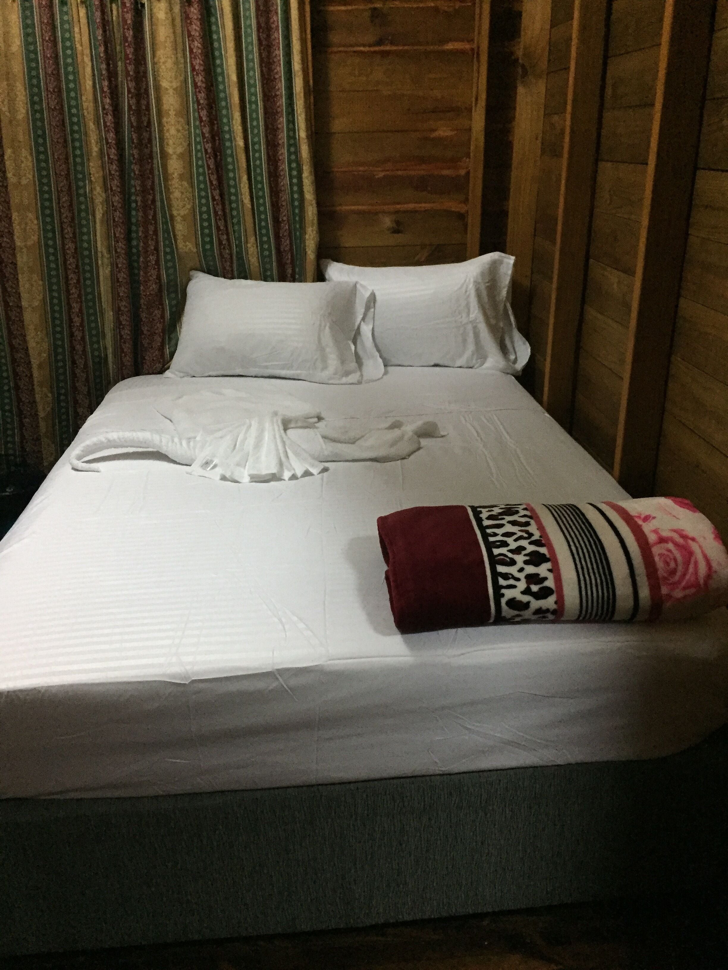 A neatly made bed with white linens and a decorative pillow.