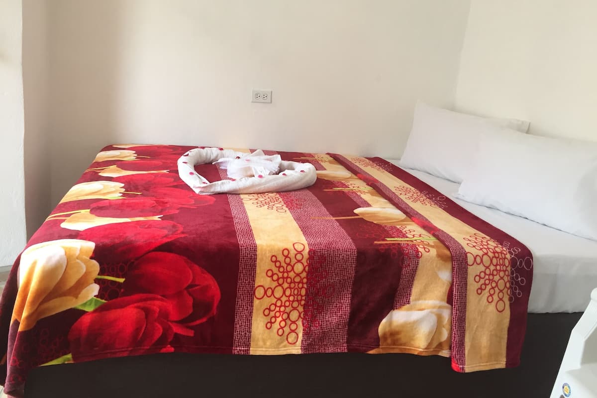 A bed with a floral-patterned bedspread, a white pillow, and a white towel.