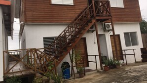 A two-story building with a wooden staircase leading to the entrance, potted plants, and a visible door number "01". - Matus Guest House (San Ignacio)