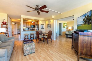 A spacious living area with a dining table, chairs, a sofa, and a television.