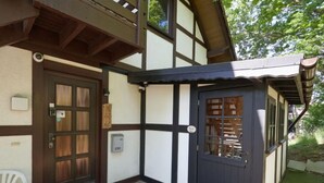 Un bâtiment traditionnel avec une porte en bois sombre et un petit porche.