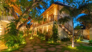A multi-story building with a staircase leading to the upper floor, surrounded by lush greenery and a stone pathway. - CasaLô Hotel (Jijoca de Jericoacoara)