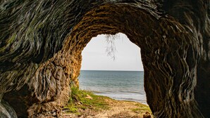 A natural rock formation with a cave-like opening leading to a sandy beach and the ocean. - CasaLô Hotel (Jijoca de Jericoacoara)