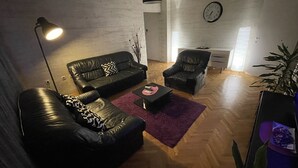Un salon moderne avec un canapé en cuir noir, un fauteuil noir, une table basse et une grande plante.