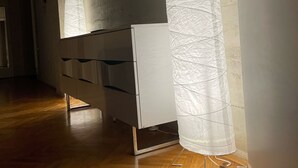 Un couloir doté d’un plancher en bois, d’une armoire blanche, d’une horloge murale et d’un grand objet blanc qui semble être un élément décoratif ou un meuble.