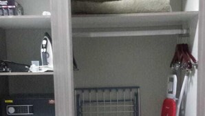 A storage closet with shelves, a radiator, and a red ironing board. - Apartmento Rosebank (Johannesburg)