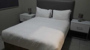A standard hotel room with a single bed, two bedside tables, and a nightstand. - Apartmento Rosebank (Johannesburg)