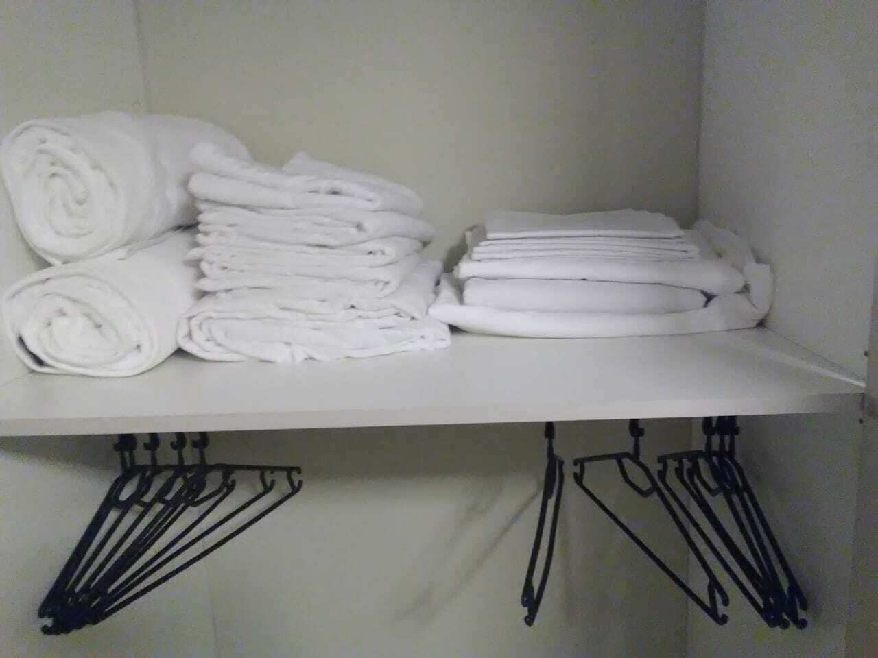 A white shelf with neatly folded white towels and a black metal rack below.
