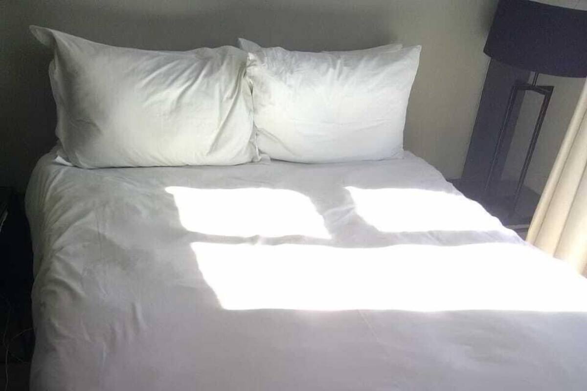 Ein Bett mit weißer Bettwäsche in einem Zimmer mit dunklem Boden.