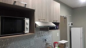 A kitchen with a microwave, a stainless steel range hood, and a refrigerator. - Apartmento Rosebank (Johannesburg)