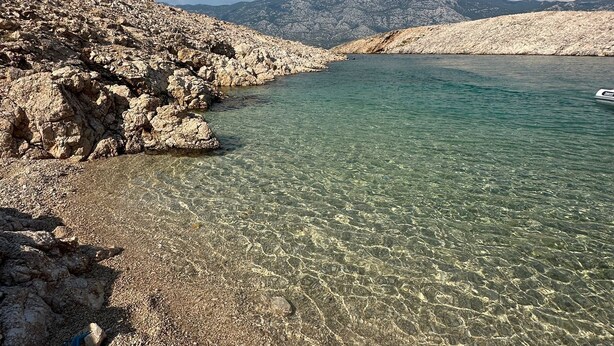 A rocky shoreline with clear water and distant mountains. - House Petra on the beach-sea (Cesarica)