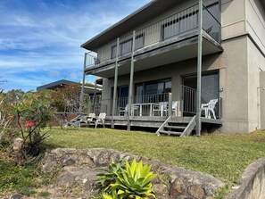 A two-story building with a balcony, outdoor seating, and a stone retaining wall.
