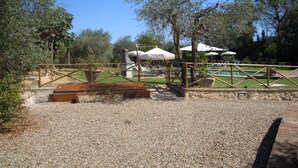 A gravel area with a pool, umbrellas, and outdoor seating. - single house in tuscany (SIENA)