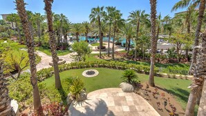 A resort with a pool area surrounded by palm trees and well-maintained lawns.