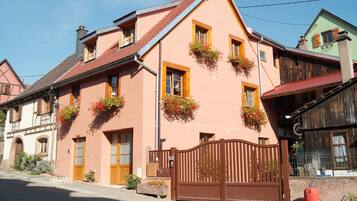Um edifício de estilo europeu tradicional com portão de madeira, várias janelas e caixas com flores.