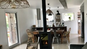 Ein modernes Wohnzimmer mit einem Holztisch, einem schwarzen Sofa und einem zentralen Kamin.