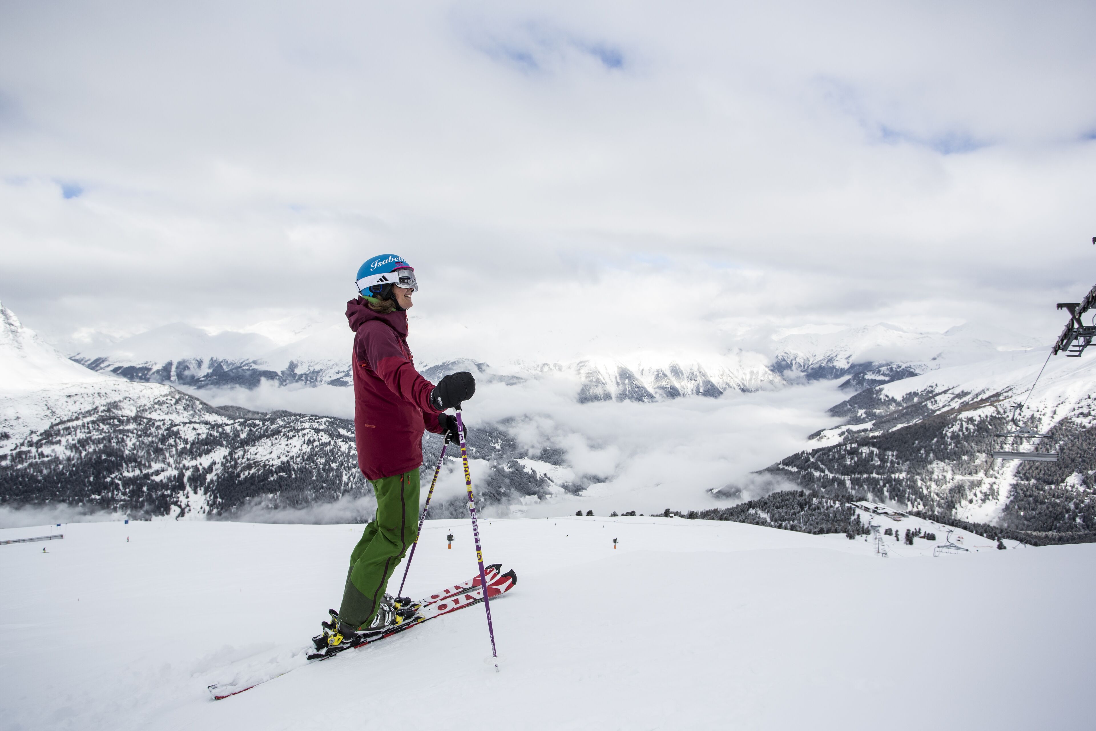 A person skiing on a snowy mountain with a ski lift in the background.