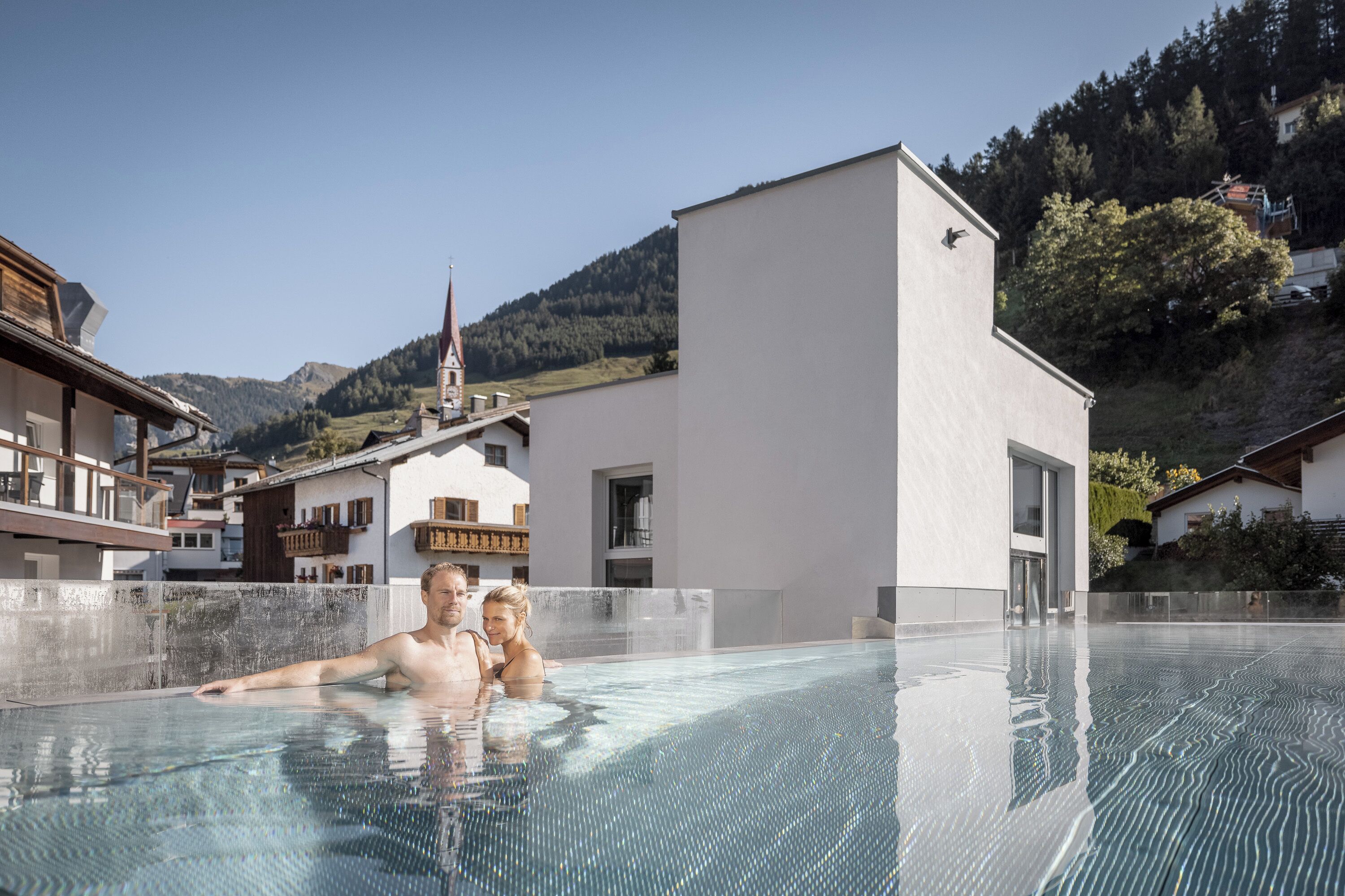 A swimming pool area with a view of a mountain and a building with a balcony.