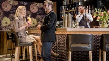 A bar area with wooden stools, a counter with bar tools, and a floral wall backdrop.