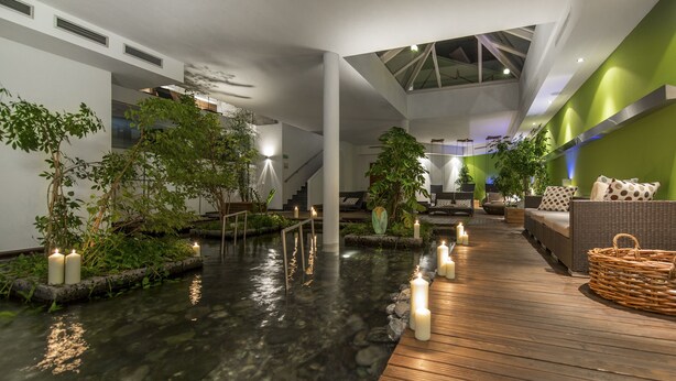 A modern indoor space with a water feature, wooden deck, and seating area. - Hotel Naudererhof (Nauders)