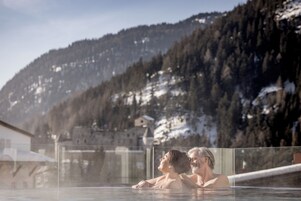 A couple in a hot tub with a mountainous backdrop.