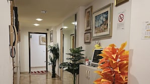 A reception area with a reception desk, a large mirror, framed artwork, and a potted plant. - Ca’ Dei Fiori 1 Venezia (Mestre)