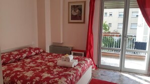 A bedroom with a bed, a nightstand, a red curtain, and a window with a view of buildings. - Ca’ Dei Fiori 1 Venezia (Mestre)