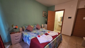 A bedroom with a bed, pillows, a nightstand, a dresser, and a bathroom visible through an open door. - Ca’ Dei Fiori 1 Venezia (Mestre)