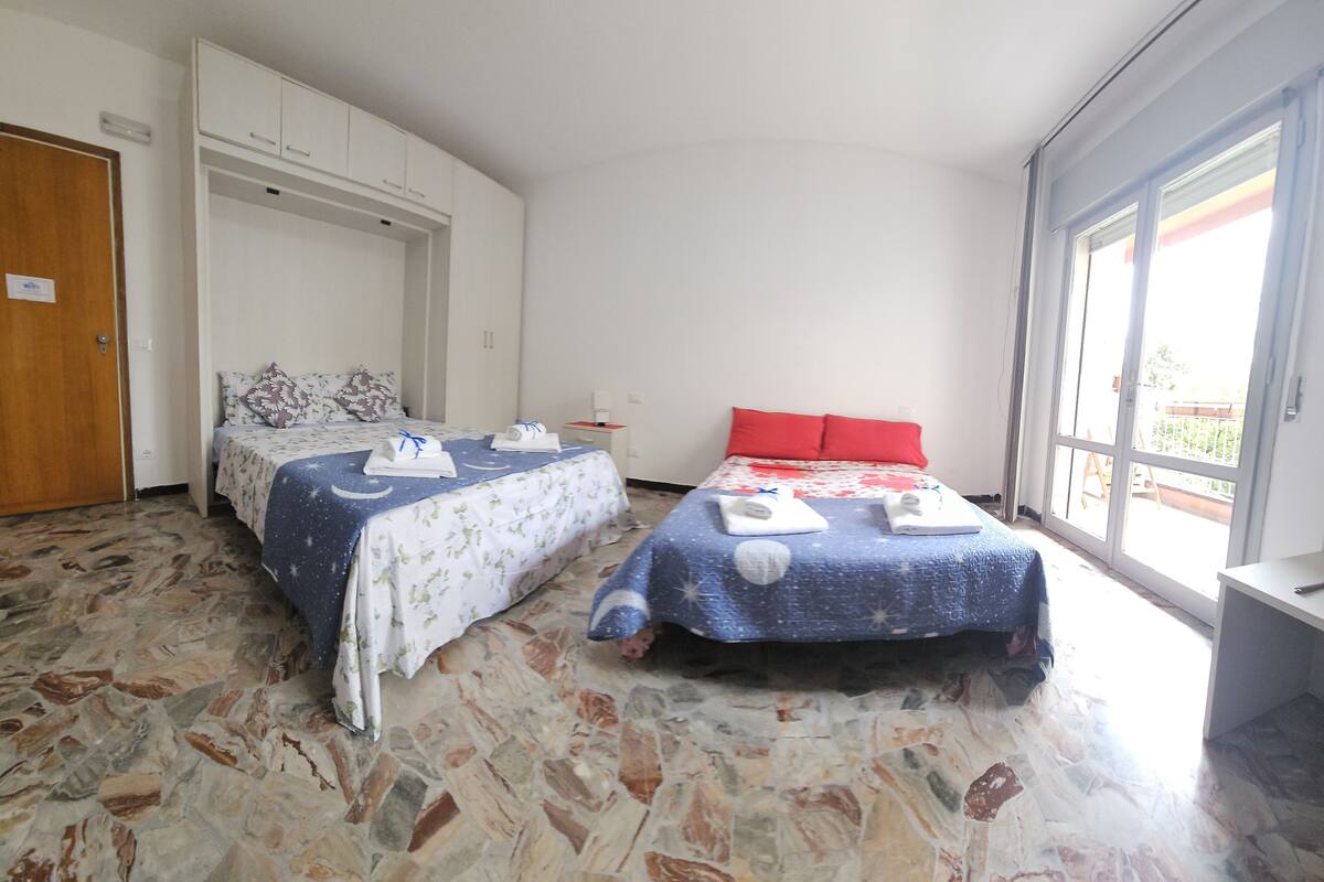 A room with two beds, a wardrobe, a small table, and a window.