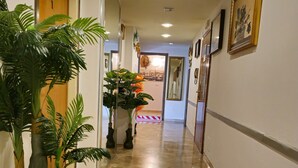 A hallway with a tiled floor, potted plants, framed artwork, and a door at the end. - Ca’ Dei Fiori 1 Venezia (Mestre)