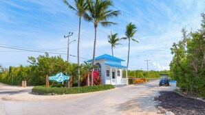 A small, single-story building with a blue roof and a porch, surrounded by palm trees and greenery. - Catch the Day, Toast the Night- Fish, Dive & Island Vibes! (Tavernier)