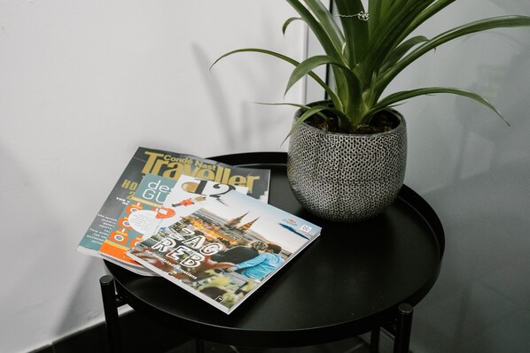 A magazine on a table with a potted plant beside it.
