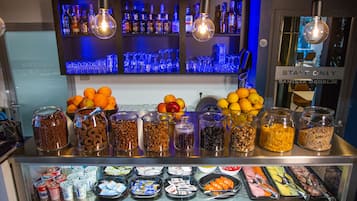 A buffet with various food items and a bar area with bottles.