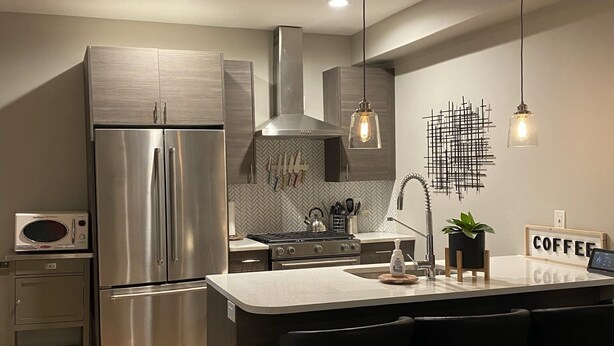 A modern kitchen with stainless steel appliances, a herringbone backsplash, and a central island with bar stools. - Victorian Home in Denver's Hip Highlands Square (Denver)