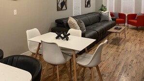 A modern living room with a black leather sofa, red chairs, a white dining table, and a wooden floor. - Victorian Home in Denver's Hip Highlands Square (Denver)