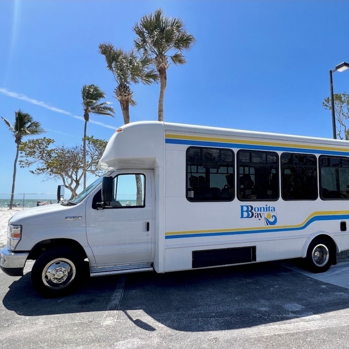 Ein weißer Bus mit 'Bonita Bay' Schriftzug vor einem Strand.