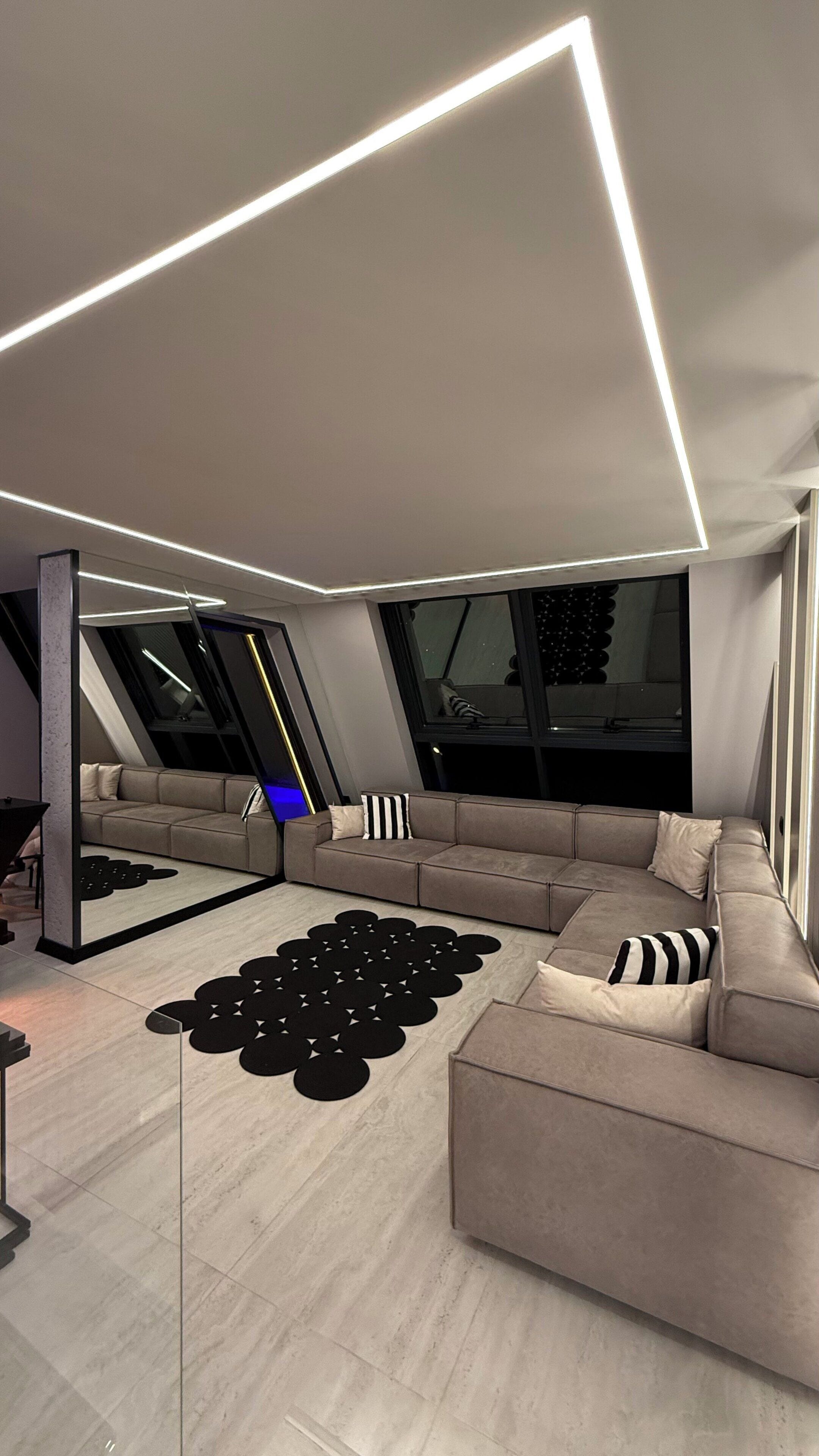 A modern living room with a sectional sofa, a black circular rug, and a large window.
