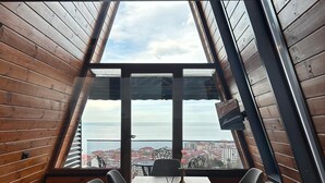 A dining area with a table, chairs, and a view through large windows. - Loya Butik Otel - Bungalow (Çayeli)