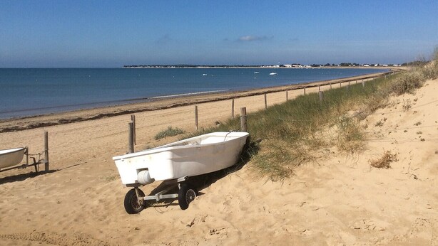 A beach with a small boat on a trailer and a sandy path.