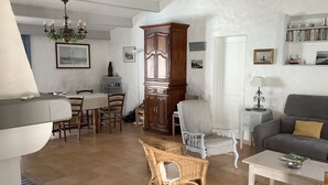 A spacious living room with a dining area, a sofa, a coffee table, and a bookshelf.