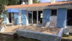 A house with a patio, blue shutters, and outdoor furniture.
