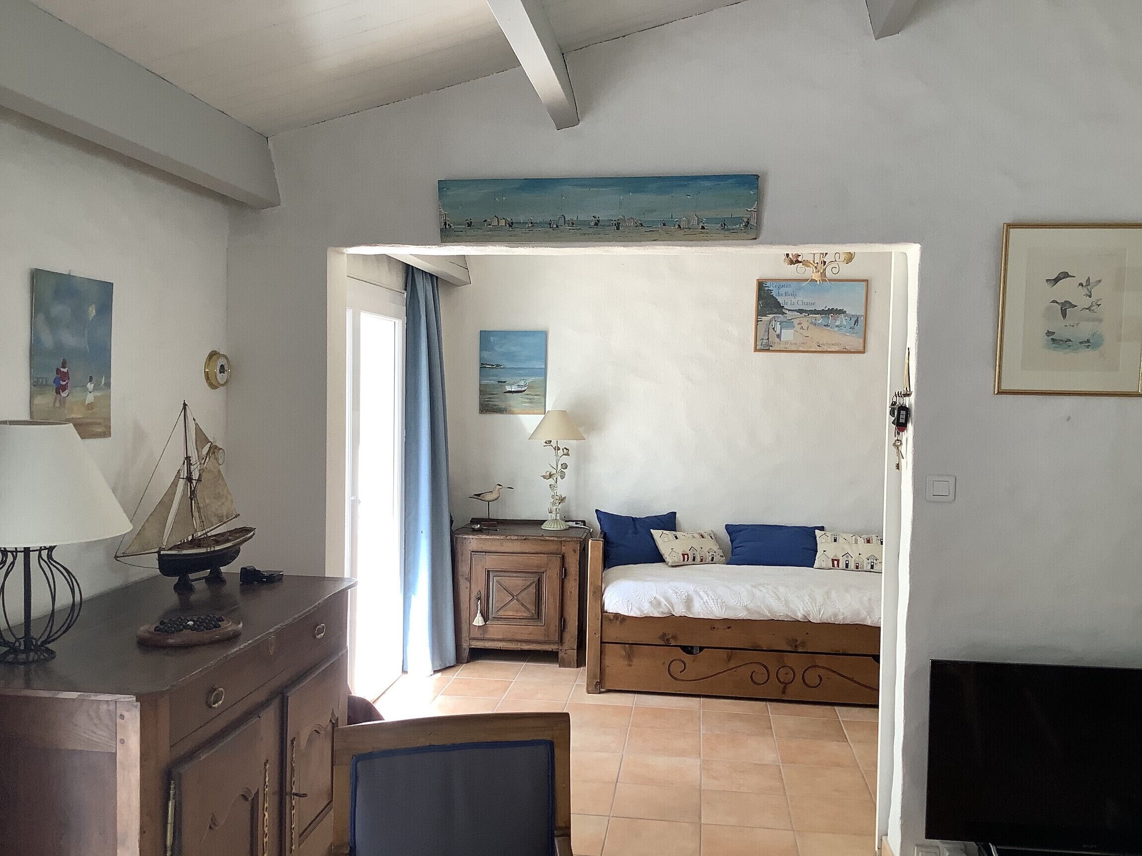 A bedroom with a bed, a desk, a chair, a lamp, and a painting on the wall.