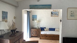 A bedroom with a bed, a desk, a chair, a lamp, and a painting on the wall.