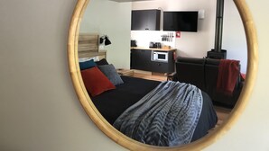 Un dormitorio moderno con cama, mesita de noche, escritorio, sofá y televisión.