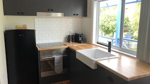 Una cocina moderna con un refrigerador negro, horno empotrado, cafetera y ventana con vistas al exterior.