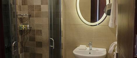 A modern bathroom with a glass shower enclosure, a sink with a mirror, and a towel rack.