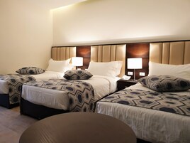 Habitación de hotel con dos camas, cada una con ropa de cama estampada y cabecero. Hay lámparas de noche y un teléfono en la mesita de noche.