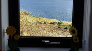 A window with a view of a lake and hills. - Private  Croft House in the Western Isles 
STL Licence Number ES00069F (Scotland)